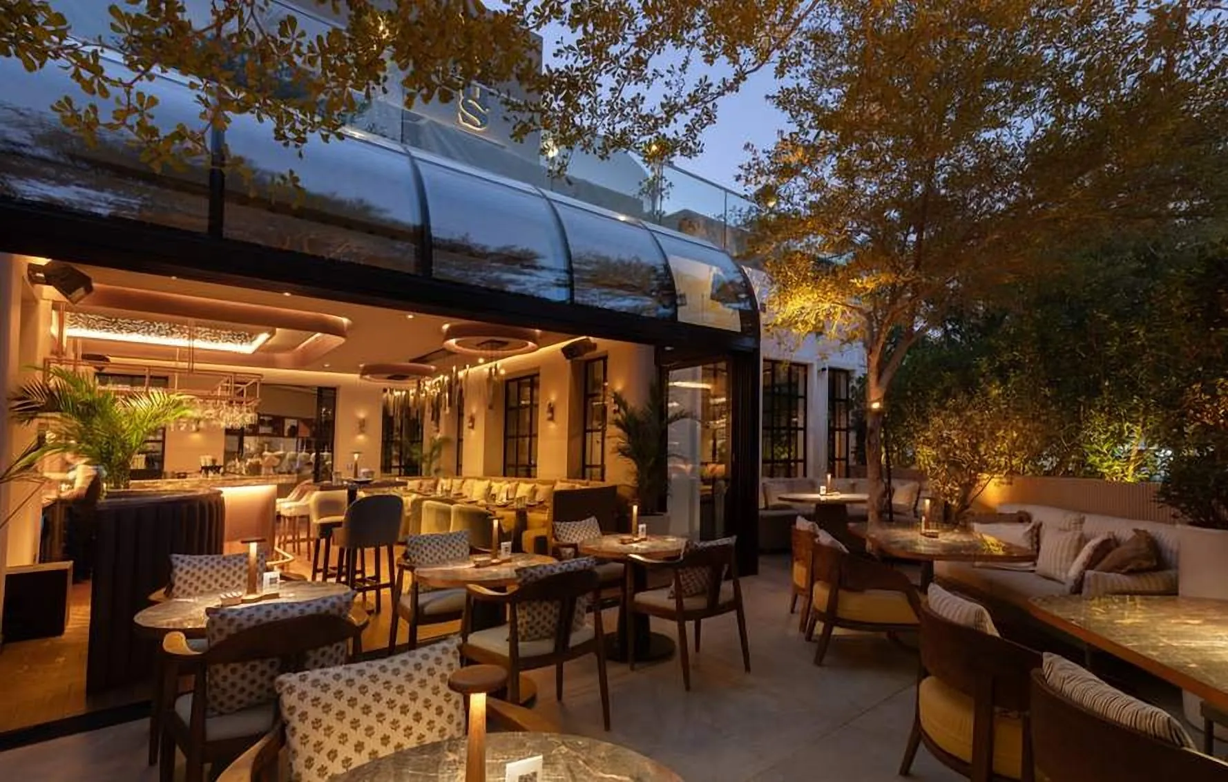 Glazed garden conservatory with dining tables at dusk