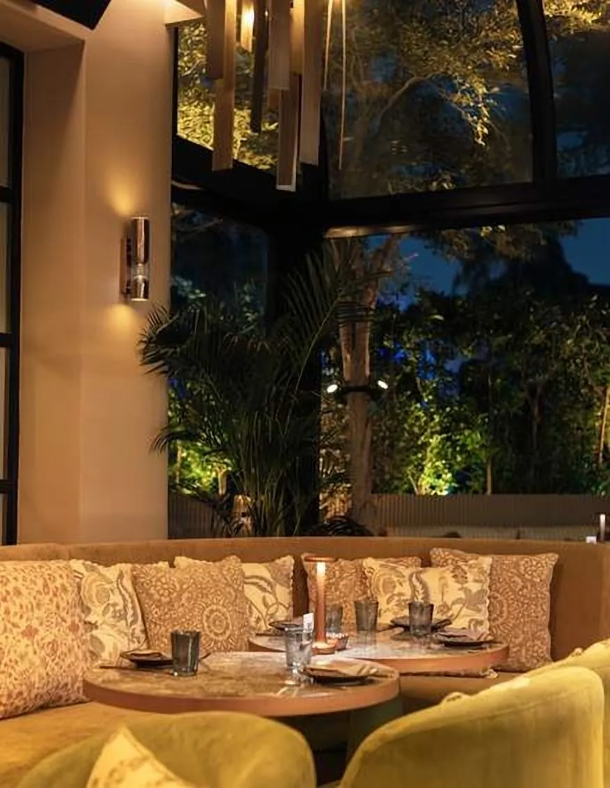 Banquette seating with yellow cushions under the glass roof