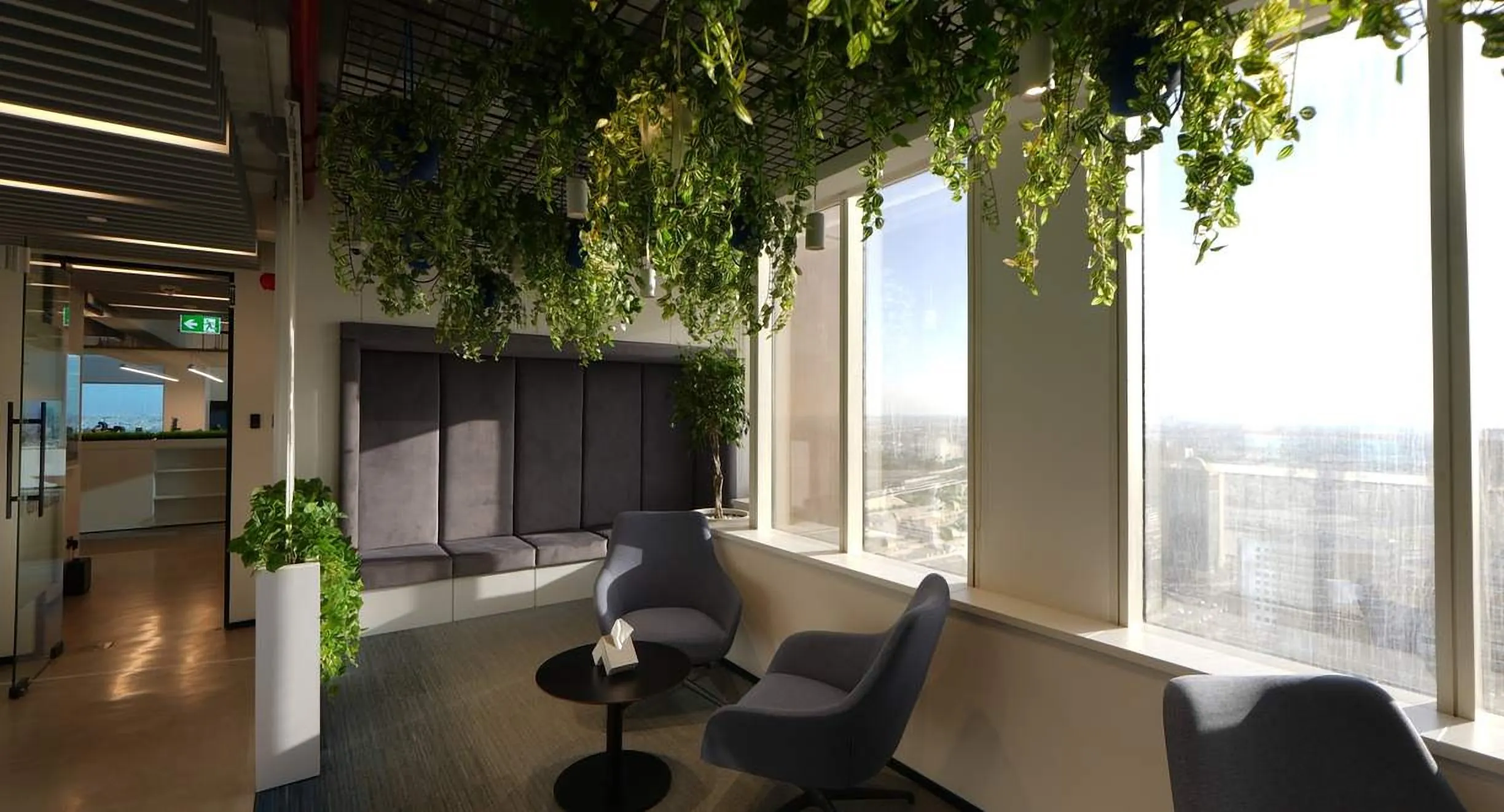 Lounge under a planted ceiling beside tall windows