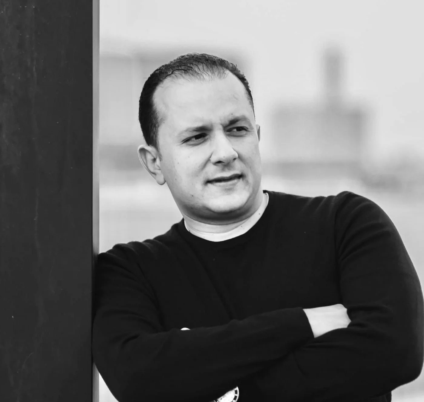 Portrait of Bashar M. Telesi in a dark sweater, arms folded
