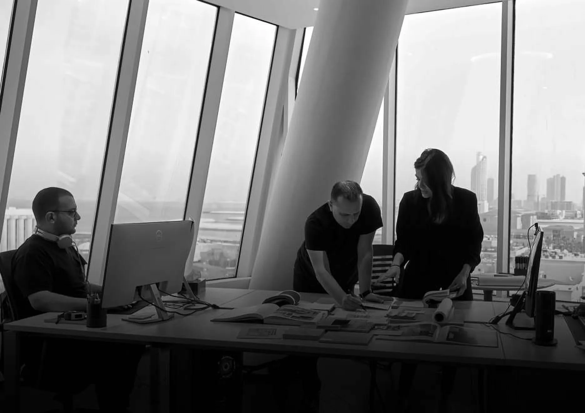 The studio team working around a table of drawings by tall windows