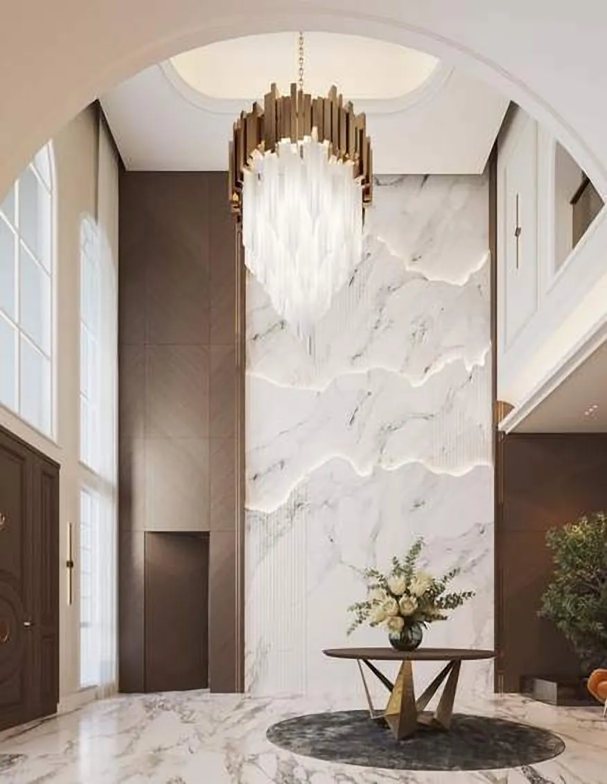 Double-height entrance with a sculpted white wall and chandelier